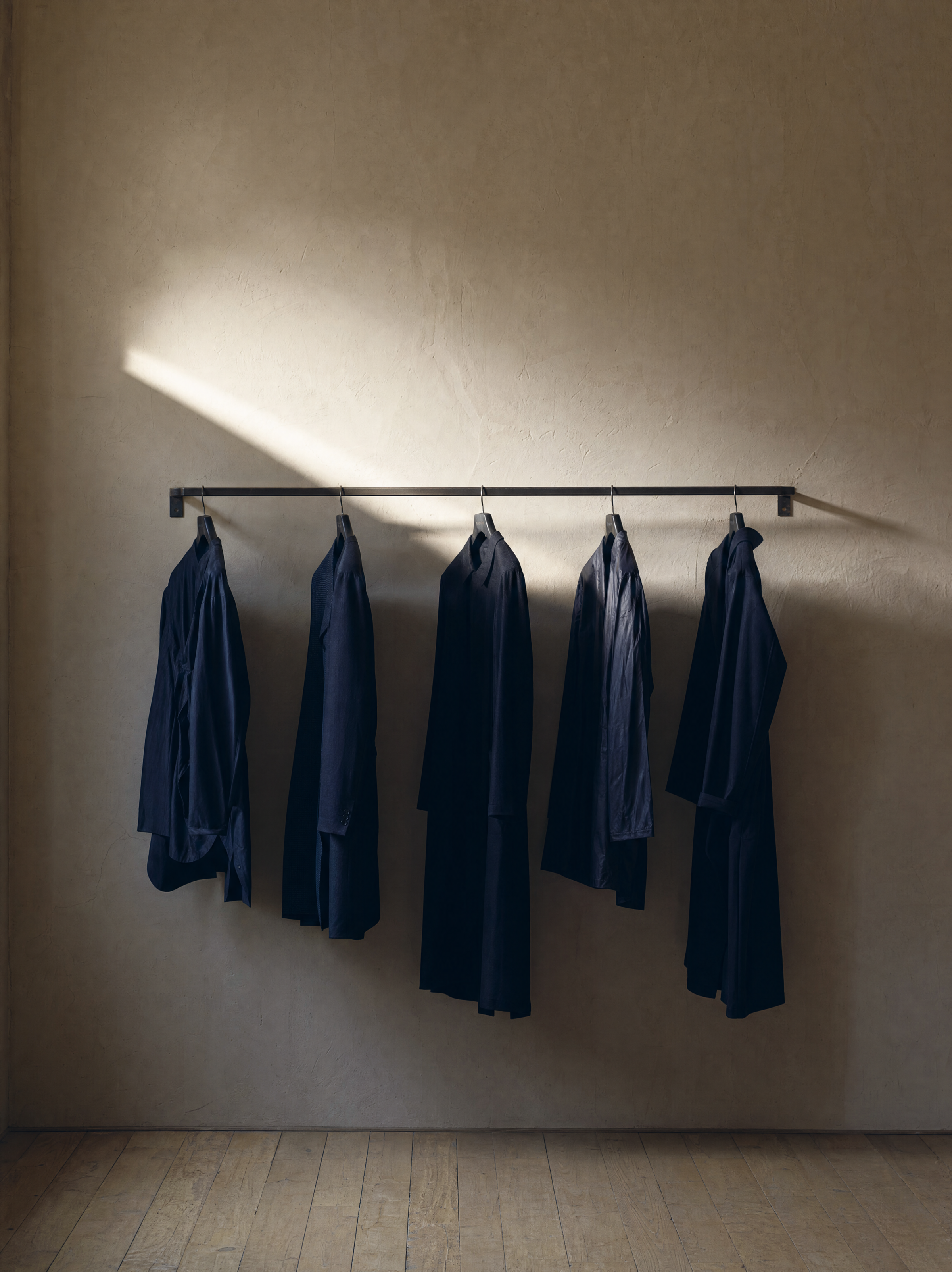 Menswear hanging on a wooden rail in soft daylight