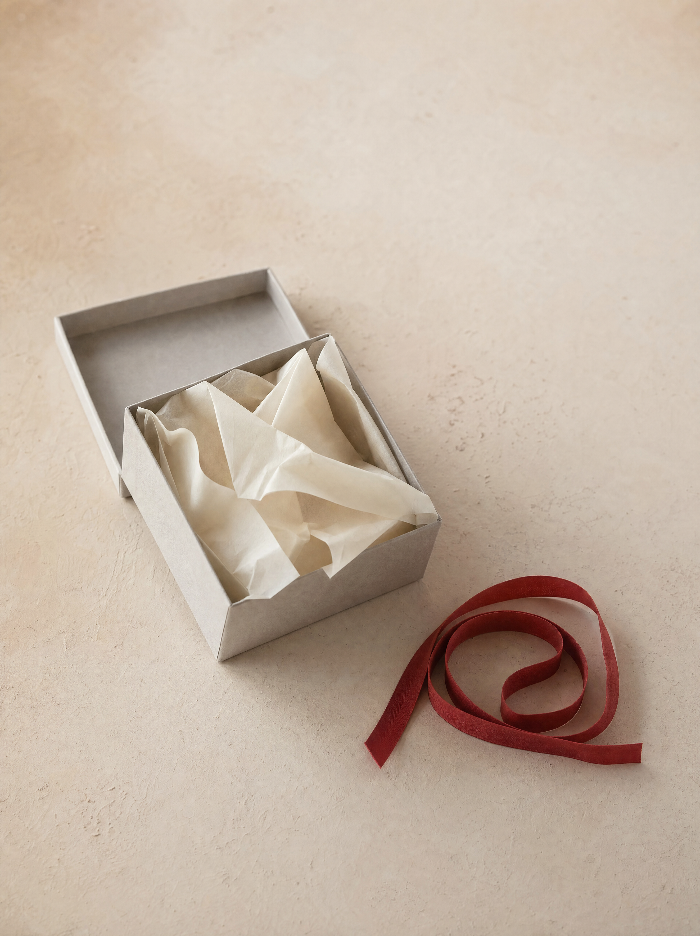 A folded garment wrapped in tissue paper inside an open Gilbert Maxwell box