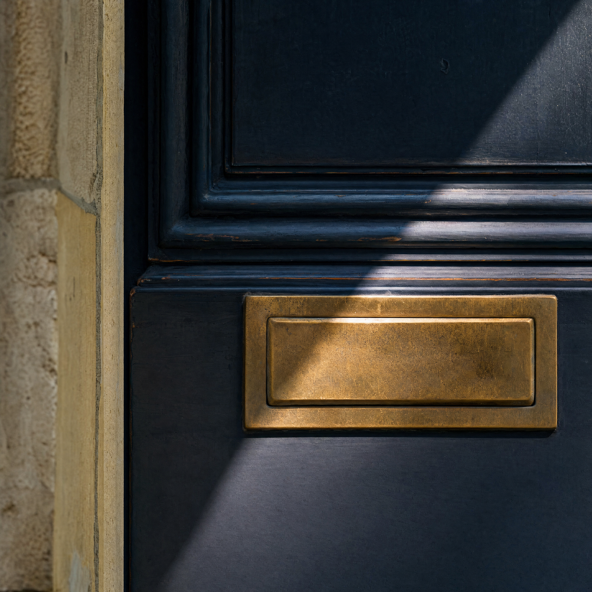 Aged brass mail slot set into a deep navy door